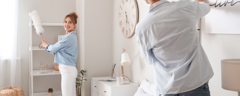 Couple cleaning the guest bedroom