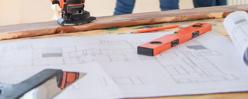 A building plan, a saw, an angle grinder and a spirit level on a workman's bench