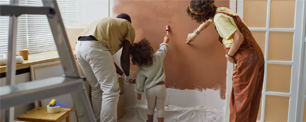 A father, mother and daughter painting a wall at home during a renovation project
