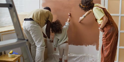 A father, mother and daughter painting a wall at home during a renovation project